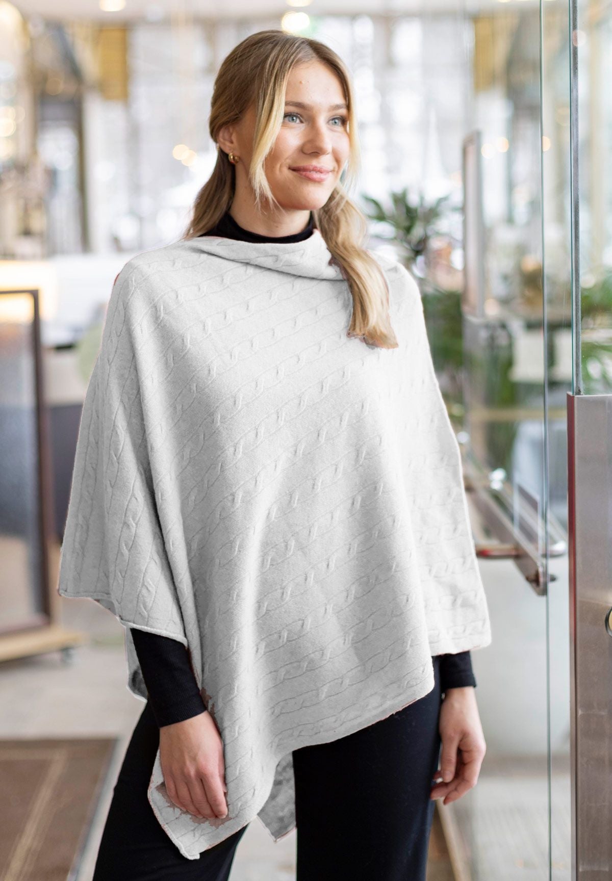 Luonnonvalkoinen palmikkoneulottu poncho naisen päällä, pehmeä ja elegantti kerrospukeutumiseen