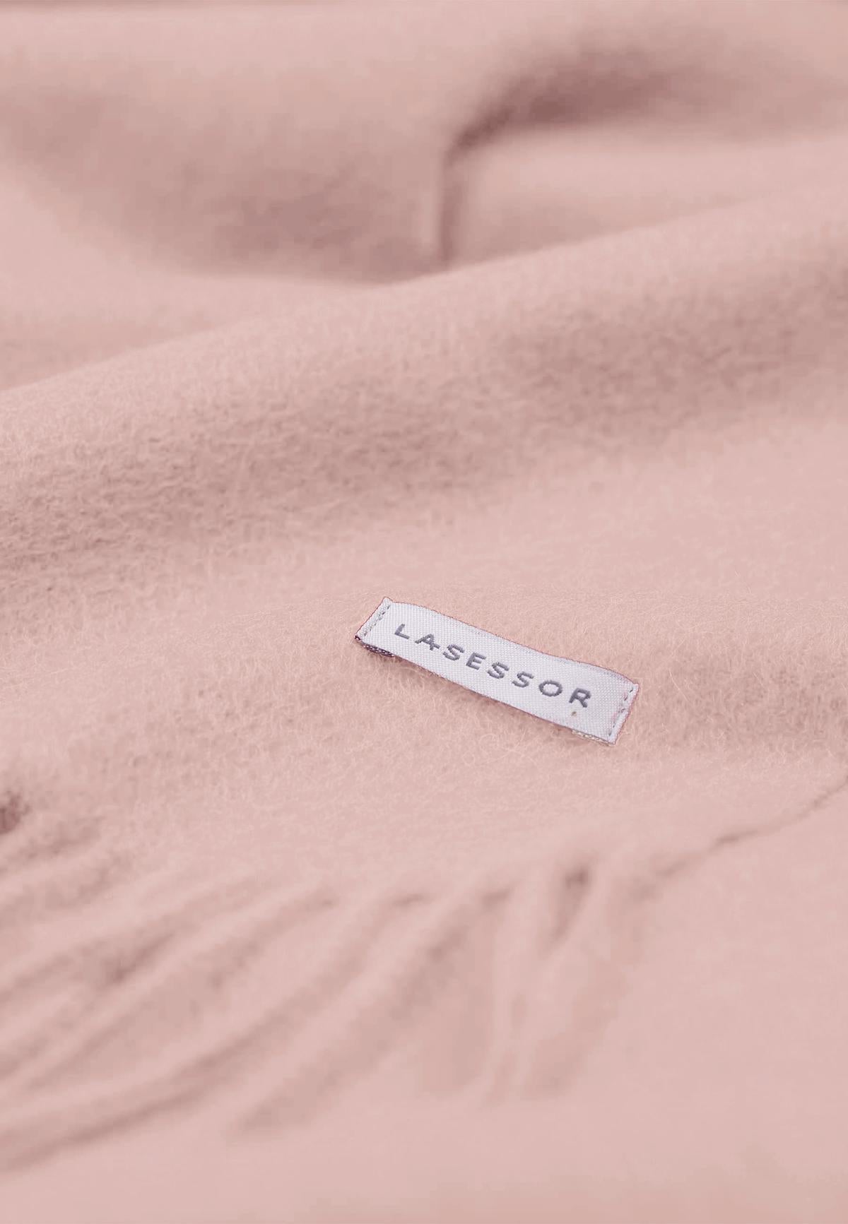 Lasessor logolla varusteltu vaalean rosa villakaulahuivi lähikuvassa.