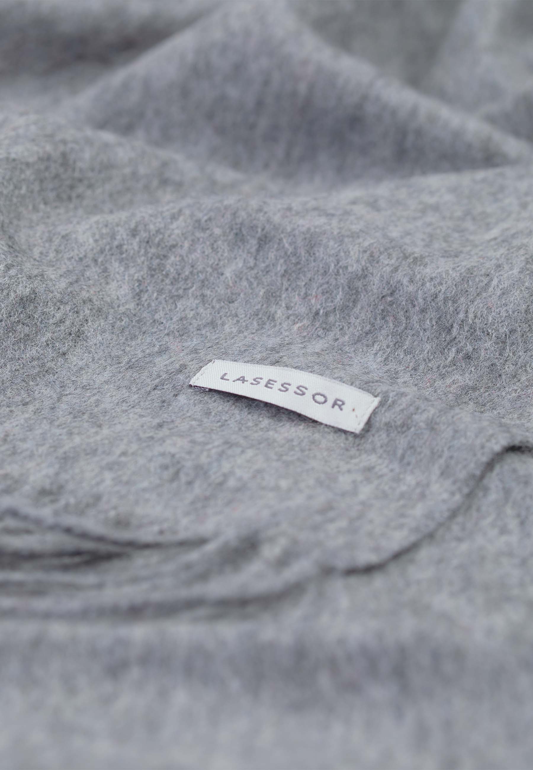 Lähikuva harmaasta design villakaulahuivi, jossa Lasessor logo.