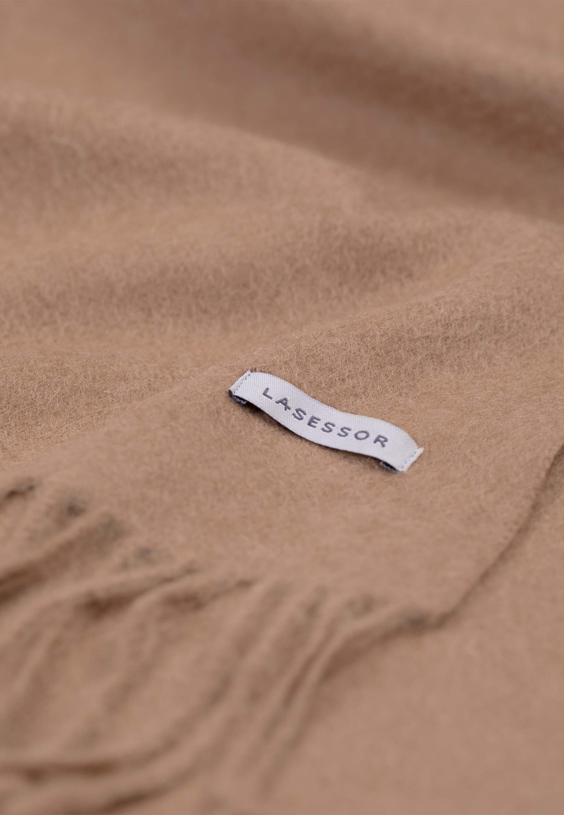 Lähikuva design villakaulahuivi värissä beige, jossa Lasessor logo.