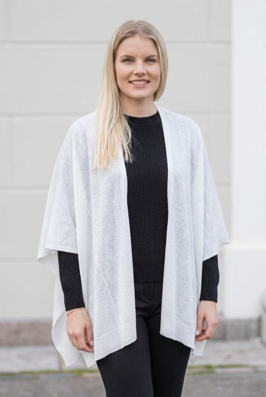 Valkoinen Siri-viitta naisen päällä ulkona, raikas ja elegantti ilme. Pehmeä neulos lämmittää kevyesti ja täydentää asun.