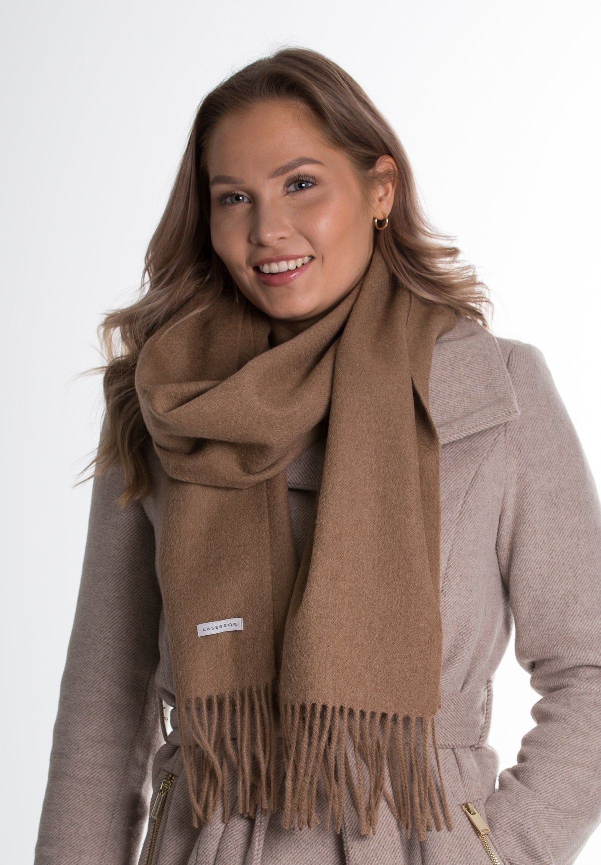 Kuva beigestä villakaulahuivi hymyilevällä mallilla valkoisella taustalla.